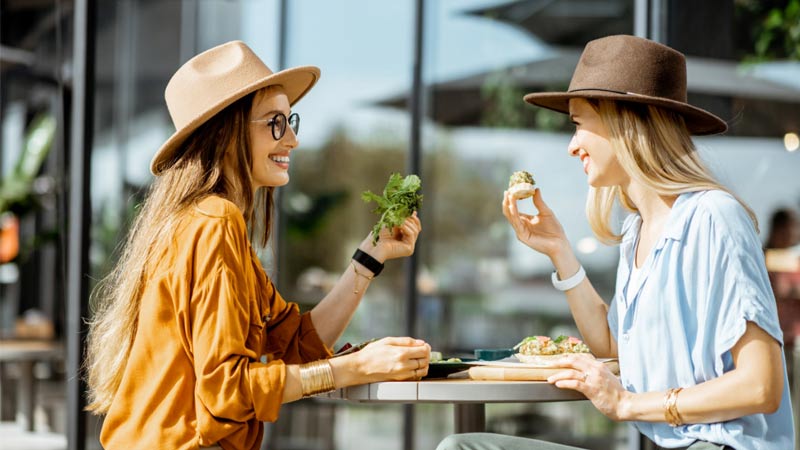 Mujeres charlando mientras almuerzan al aire libre